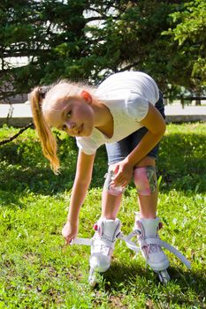 Cute girl put on roller skates in summer