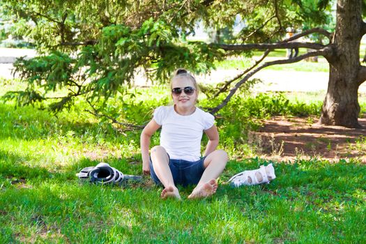Cute girl put on roller skates in summer