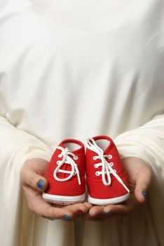 A mother embraces her childs shoes to welcome a new beginning.