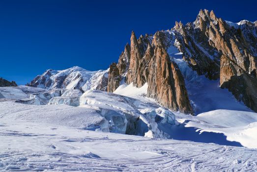 Picturesque view of a snowy plain with mountain peaks above                