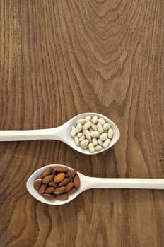 nuts in new wooden spoons on oak plank background. Healthy food