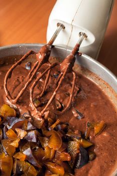 Stirring with electric whisk the ingredients for a chocolate cake with fruits