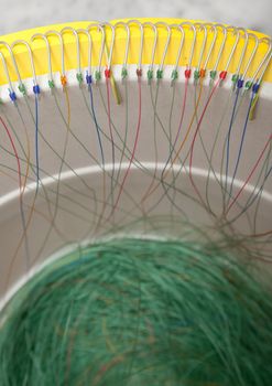 The longline is being prepared for fishing. The hooks are nailed on the perimeter edge of the yellow plastic bowl.