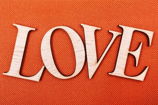 Wooden letters forming word LOVE written on orange background