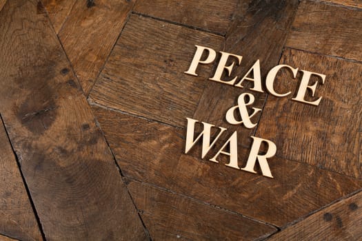 Wooden letters forming words PEACE & WAR written on old vintage wooden plates with space for your own text.