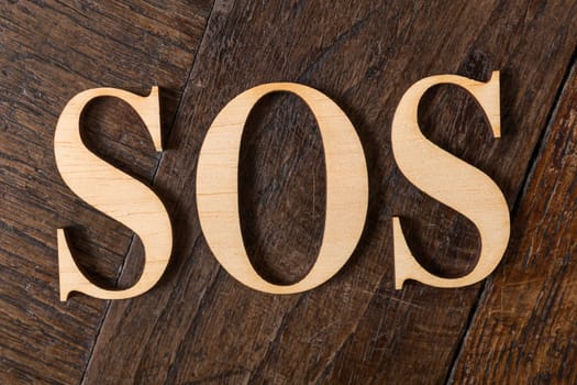 Wooden letters forming word SOS written on old vintage wooden plates