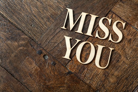 Wooden letters forming words MISS YOU written on old vintage wooden plates with space for your own text.