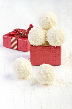 Coconut snowball truffles in the gift box on white background. Arrangement of coconut cookies on wooden elegant background.