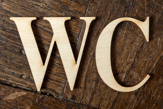 Wooden letters forming word WC written on old vintage wooden plates