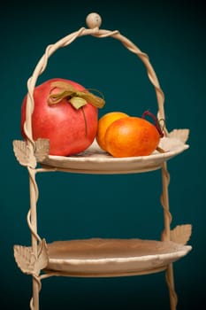 Two Easter eggs with a pomegranate on a base on a green background