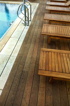 Wooden sunbeds next to a swimming pool