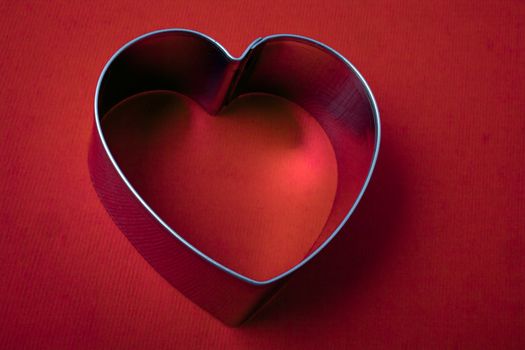 A vintage metal heart shaped sugar dough cookie cutter on red background