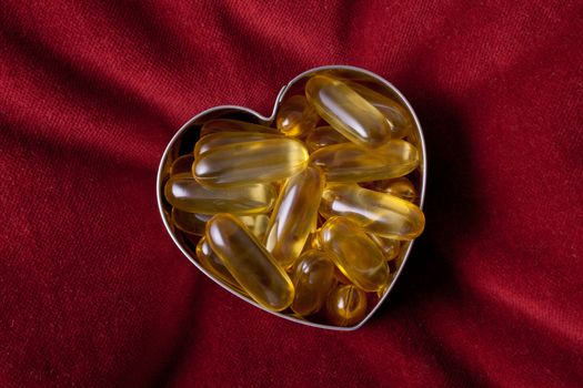 Vitamin capsules arranged in the shape of a heart to portray the concept of a healthy heart and lifestyle