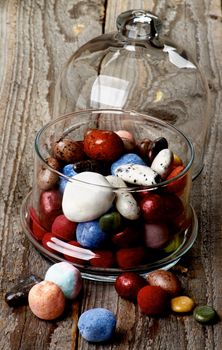 Various Colored Gum and Hard Candies in Glass Jar with Lid closeup on Rustic Wooden background