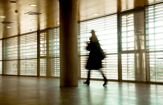 Intentional motion blurred image of a business people group walking in office lobby. All exposed faces are motion blurred.