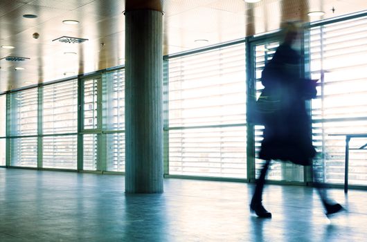 Intentional motion blurred image of a business people group walking in office lobby. All exposed faces are motion blurred.