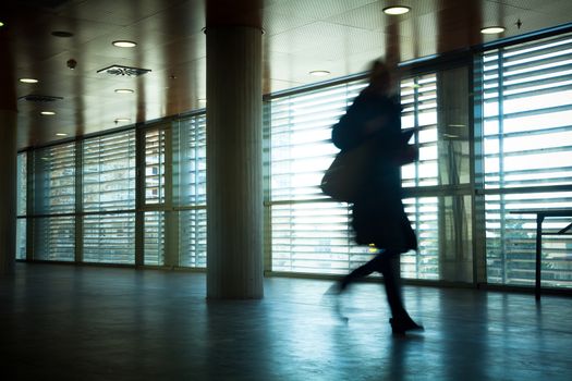 Intentional motion blurred image of a business people group walking in office lobby. All exposed faces are motion blurred.