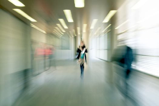 Intentional motion blurred image of a business people group walking in office lobby. All exposed faces are motion blurred.