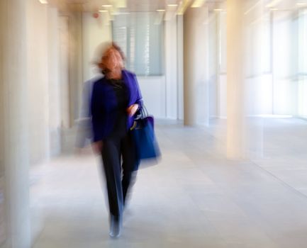 Intentional motion blurred image of a business people group walking in office lobby. All exposed faces are motion blurred.