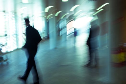 Intentional motion blurred image of a business people group walking in office lobby. All exposed faces are motion blurred.