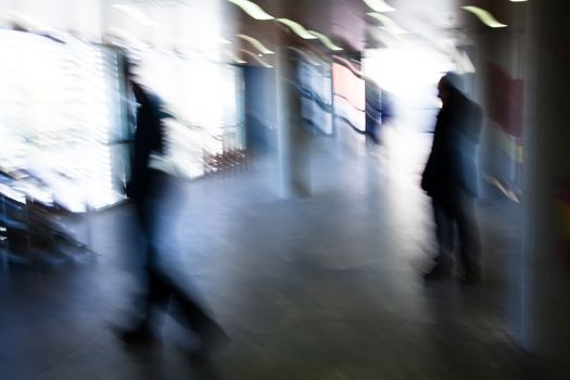 Intentional motion blurred image of a business people group walking in office lobby. All exposed faces are motion blurred.