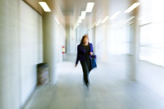 Intentional motion blurred image of a business people group walking in office lobby. All exposed faces are motion blurred.