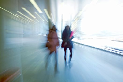 Intentional motion blurred image of a business people group walking in office lobby. All exposed faces are motion blurred.