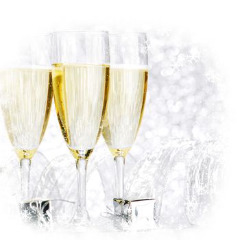 Glasses of champagne and silver gifts on glitter background