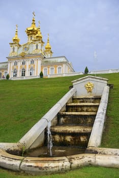 small cascading fountain on the background Domestic Church of Peter and Paul in Peterhof Grand Palace, Saint Petersburg