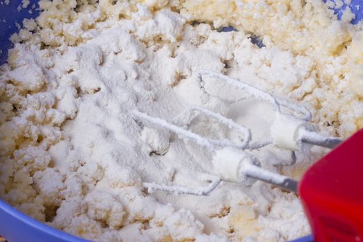 Mixer beat the dough in a blue bowl