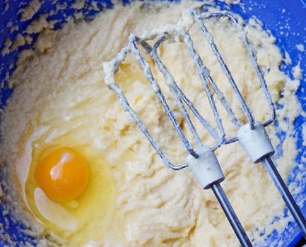Mixer beat the dough in a blue bowl