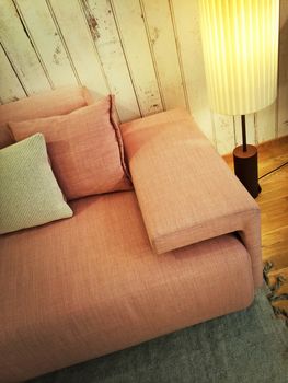 Retro style pink sofa with cushions and floor lamp.