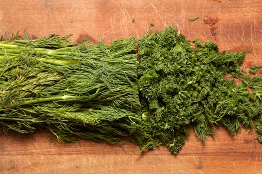 Fresh dill sprigs on wooden board cutting with knife