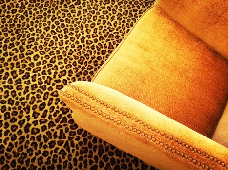 Orange velvet armchair on a fancy leopard carpet.