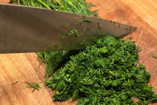 Fresh dill sprigs on wooden board cutting with knife