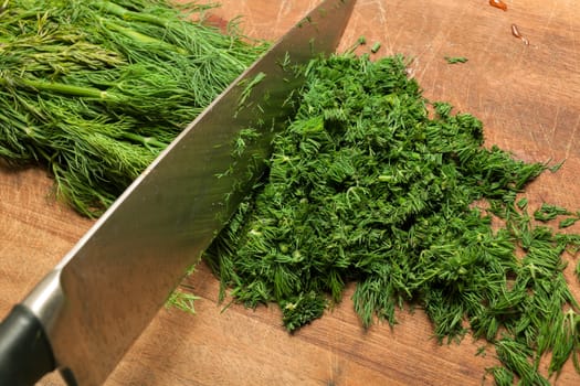 Fresh dill sprigs on wooden board cutting with knife