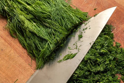 Fresh dill sprigs on wooden board cutting with knife