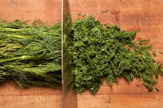 Fresh dill sprigs on wooden board cutting with knife