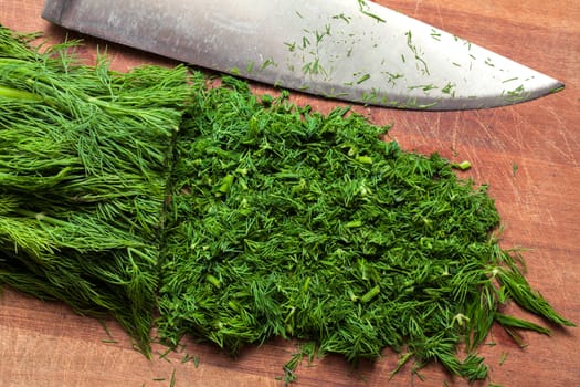 Fresh dill sprigs on wooden board cutting with knife