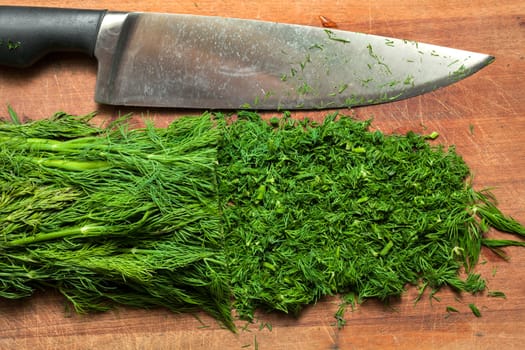 Fresh dill sprigs on wooden board cutting with knife