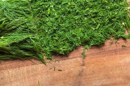 Fresh dill sprigs on wooden board cutting with knife