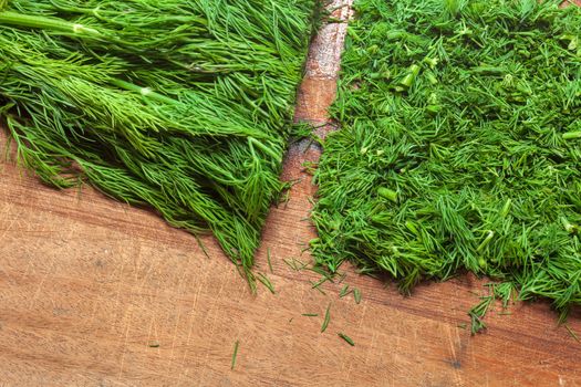 Fresh dill sprigs on wooden board cutting with knife