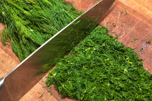 Fresh dill sprigs on wooden board cutting with knife