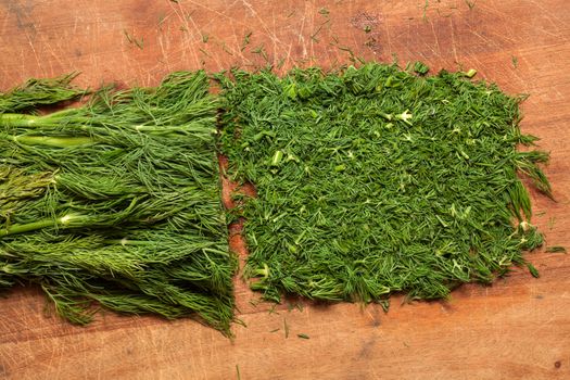 Fresh dill sprigs on wooden board cutting with knife