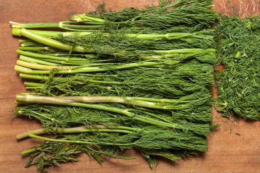 Fresh dill sprigs on wooden board cutting with knife