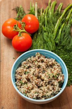 Bowl with Cereal Mix of Red and Whole Grain Quinoa on a wooden surface with dill