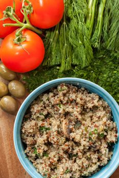 Bowl with Cereal Mix of Red and Whole Grain Quinoa on a wooden surface with dill