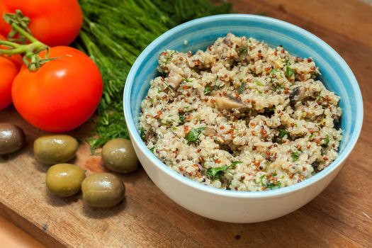 Bowl with Cereal Mix of Red and Whole Grain Quinoa on a wooden surface with dill