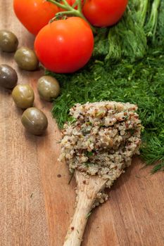 Wooden spoon with ready cooked quinoa, on a wooden surface with dill