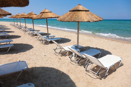 Beautiful beach with deck chairs and umbrellas on the sandy beach in Nea Irakleia (Halkidiki). Thessaloniki - Greece